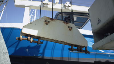 Verwittertes Metallteil mit rostigen Schäkeln an einem gekranten Boot