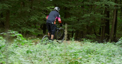 Mountainbiker fährt auf einem Waldweg durch grünes Dickicht