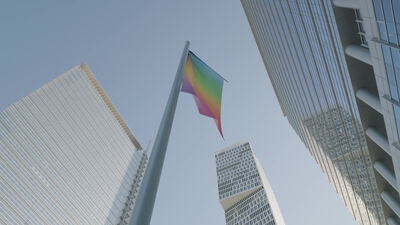 Regenbogenfahne weht zwischen gläsernen Hochhäusern