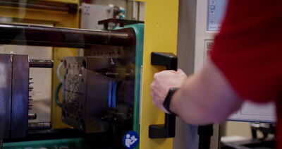 Arbeiter bedient eine Spritzgussmaschine mit offenem Werkzeug