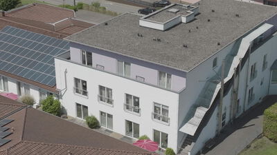 Drohnenaufnahme eines modernen Gebäudes mit Solaranlagen und Innenhof