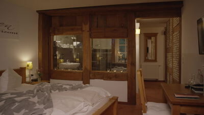 Warmes Hotelzimmer am Abend mit leuchtender Nachttischlampe