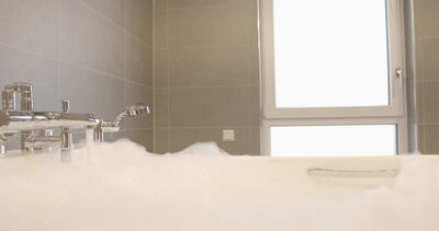 Schaumbad läuft langsam in eine Badewanne im hellen Badezimmer