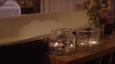 Dekorative Glasgefäße auf einer Holzbank mit rosa Blumen