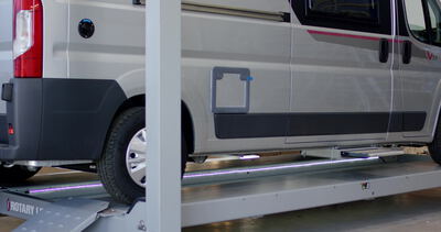 Weißer Transporter steht zur Wartung auf einer Hebebühne in der Werkstatt: Transporter, Nutzfahrzeug
