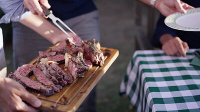 Aufgeschnittenes Steak wird beim Grillfest auf einem Holzbrett serviert