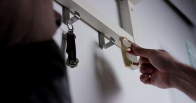 Hand greift nach dem goldenen Türöffner an der Garderobe