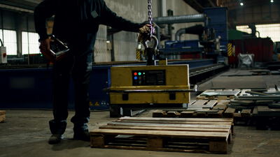 Arbeiter steuert Lastmagnet in einer Halle der Metallverarbeitung