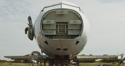 Frontansicht eines Flugzeugrumpfs mit geöffnetem Bugsegment im Freien