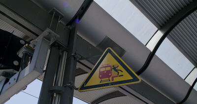 Warnschild unter dem Bahnhofsdach zwischen Stahlträgern
