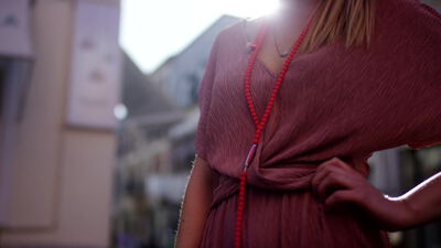 Frau im rosa Sommerkleid mit roter Perlenkette auf der Straße Frau im rosa Sommerkleid mit roter Perlenkette auf der Straße, Frau im Sommerkleid, rosa Kleid und rote Perlenkette als 4K