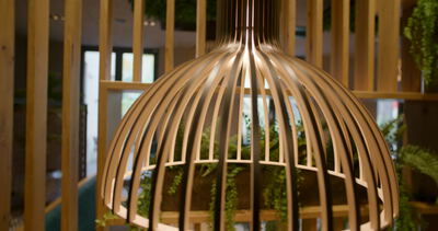 Holzkorbleuchte erhellt eine moderne Restaurantecke mit Pflanzenwand