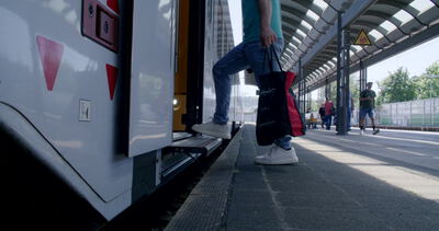 Person geht mit Tasche über den Bahnsteig unter dem Bahnhofsdach