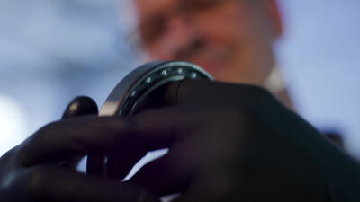 Prüfung eines Kugellagers mit Handschuhen in der Qualitätskontrolle