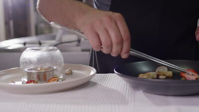 Koch richtet ein Gourmetgericht mit Rauch unter der Glasglocke an