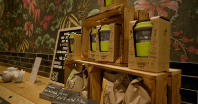 Holzkisten präsentieren Mehrwegbecher und Kaffeetüten in gemütlicher Café Theke