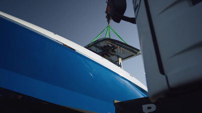 Kleines Bauteil schwebt an grünen Hebegurten neben dem Yachtbug