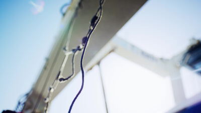 Seile mit Knoten hängen im Gegenlicht an einem Kranträger