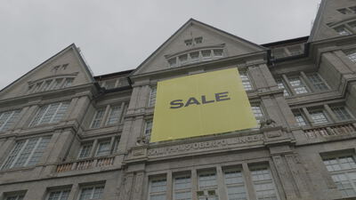 Großes Sale Banner hängt an der Fassade eines historischen Kaufhauses