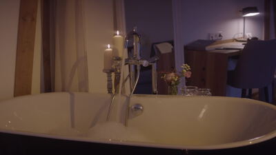 Freistehende Badewanne mit Kerze im gemütlichen Wellnessbad
