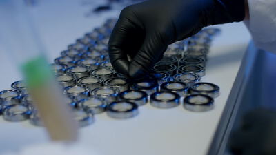 Hände in Handschuhen prüfen viele Kugellager auf heller Fläche