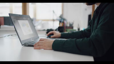 Person arbeitet am Laptop an einem hellen Schreibtisch