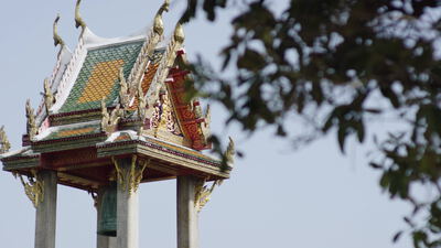 Ein reich verzierter Glockenturm eines thailändischen Tempels ragt in den Himmel