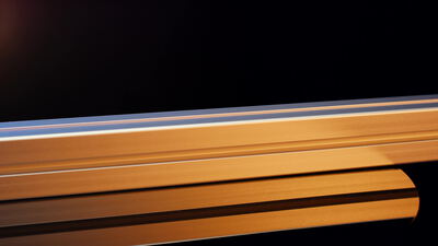 Bunte eloxierte Aluminiumprofile glänzen in Nahaufnahme vor dunklem Hintergrund