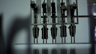 Reihe metallischer Greifer an einer Industriemaschine im kühlen Licht Reihe metallischer Greifer an einer Industriemaschine im kühlen Licht, Metallgreifer, Produktionsmaschine und