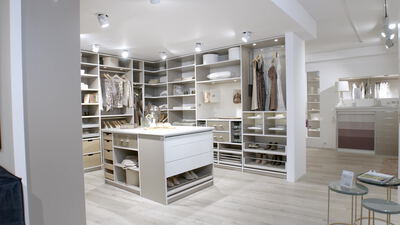 Elegantes Ankleidezimmer mit hellen Regalen und zentraler Kommode Elegantes Ankleidezimmer mit hellen Regalen und zentraler Kommode, begehbarer Kleiderschrank, Kleiderschrank und Garderobe