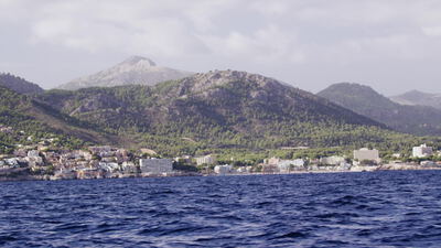 Küstenstadt am Fuß grüner Berge vom Meer aus gesehen