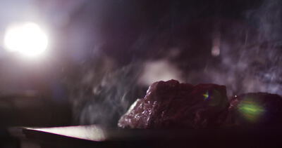 Gegrilltes Steak dampft auf einem Holzbrett im Gegenlicht
