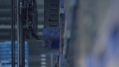 Automatisiertes Regalbediengerät bewegt blaue Kunststoffbehälter im Lager