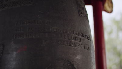 Große bronzene Tempelglocke mit Inschrift an rotem Gestell