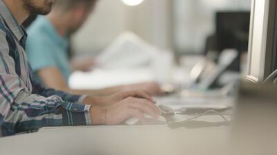 Mann tippt auf einer Tastatur am Schreibtisch im hellen Büro Mann tippt auf einer Tastatur am Schreibtisch im hellen Büro, Büroarbeit, Großraumbüro und Mann am Computer als 4K Stockvideo