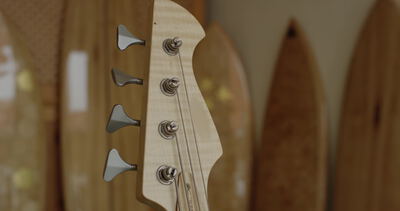 Kopfplatte eines E Basses mit Stimmmechaniken vor Surfbrettern