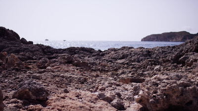 Felsige Küste mit ruhigem Meer und Landzunge am Horizont
