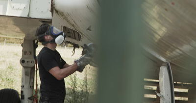 Arbeiter mit Atemschutzmaske demontiert Bauteile an einem Flugzeugrumpf