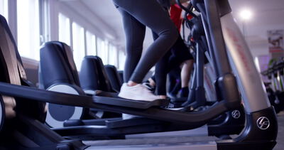 Crosstrainer steht in einem hellen Fitnessstudio mit großen Fenstern