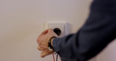 Elektriker prüft Spannung an einer Steckdose mit Messleitungen Elektriker prüft Spannung an einer Steckdose mit Messleitungen, Spannung messen Steckdose, Elektriker prüft Steckdose und