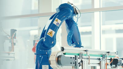 Blauer Industrieroboter über Förderband in moderner Fabrik