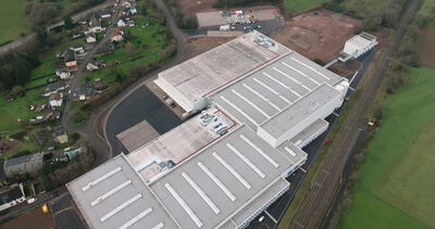 Fabrikdächer mit Oberlichtern entlang einer Bahnlinie von oben