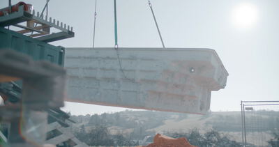 Kran hebt schweres Betonfertigteil auf einer Baustelle