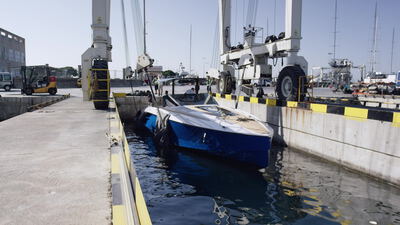 Blaues Motorboot liegt im Hafenbecken unter einem Bootskran