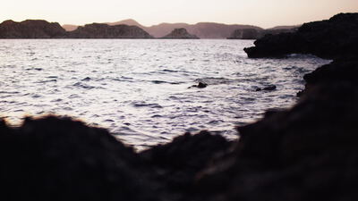 Felsige Küste mit ruhiger See in der Abenddämmerung