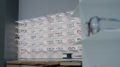 Beleuchtete Brillenwand mit vielen Modellen im Optikergeschäft