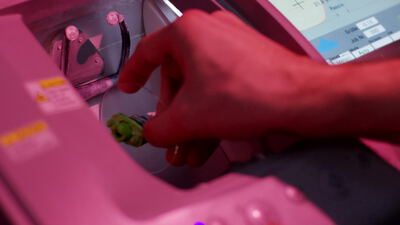 Hand bedient eine Industriemaschine mit Touchscreen im pinken Licht