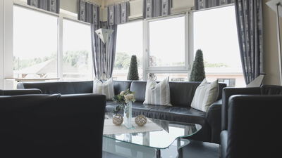 Wohnzimmer mit dunklen Ledersofas und großen Fenstern