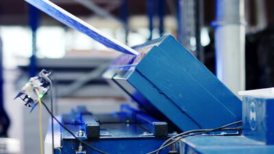 Optischer Sensor überwacht blaue Maschine in der Fabrikhalle, Industriesensor, Maschinenüberwachung und Sensorik als 4K