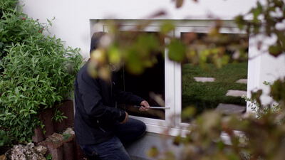 Einbrecher hebelt ein Kellerfenster am Haus auf